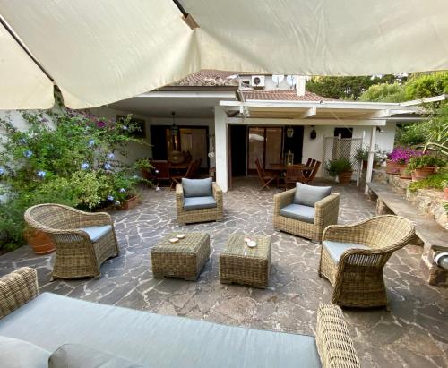 a patio with wicker chairs and tables and an umbrella at Terrazza sull Argentario in Ansedónia
