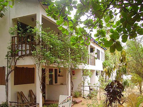 a white house with a tree in front of it at Hotel Village Vacances Awale Plage in Grand-Popo