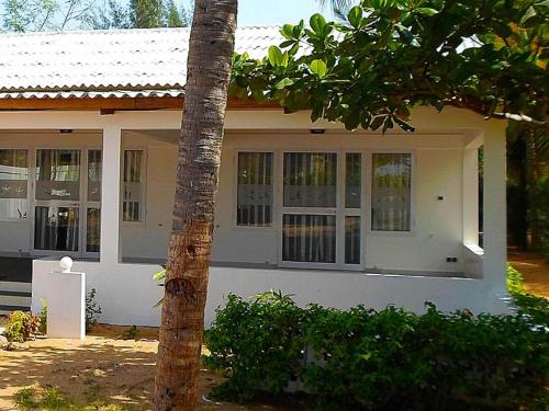 a white house with a tree in front of it at Hotel Village Vacances Awale Plage in Grand-Popo