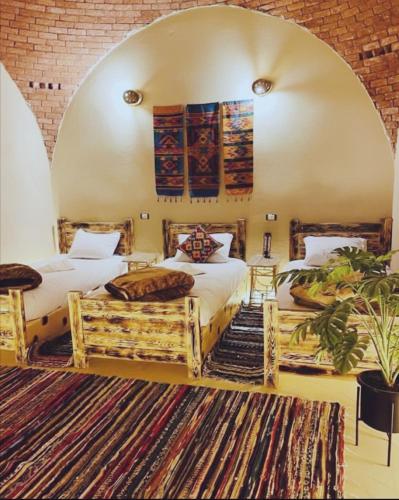 two beds in a room with an arched ceiling at Shasha Siwa Retreat & Thermal Spring in Siwa