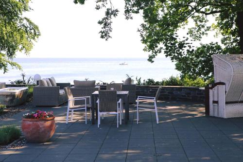 een terras met een tafel en stoelen en de oceaan bij Hotel Badehaus Goor in Putbus