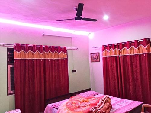 a bedroom with red curtains and a ceiling fan at saraswati home stay in Pālampur