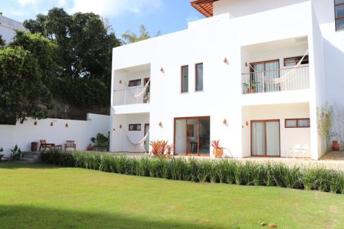 een wit huis met een gazon ervoor bij Casa Aia in Aracaju