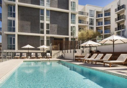 a swimming pool with chairs and umbrellas next to a building at Luxe on Hollywood Blvd 2BR with FREE PARKING in Los Angeles