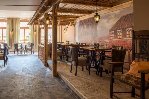 a restaurant with tables and chairs and a brick wall at Hotel Schwarzer Adler Tangermünde in Tangermünde