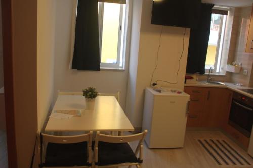 a small kitchen with a table and a refrigerator at Isaura Home in Peniche