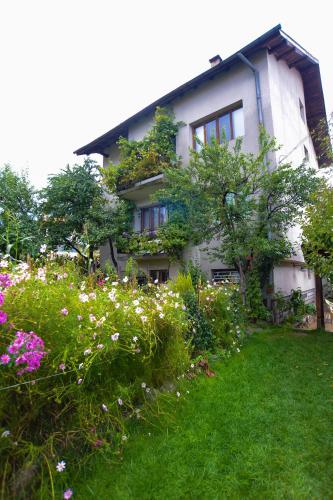 a house with a garden with flowers in front of it at Topuzovi Guest House in Dobrinishte