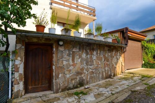 a building with potted plants on top of a stone wall at Topuzovi Guest House in Dobrinishte