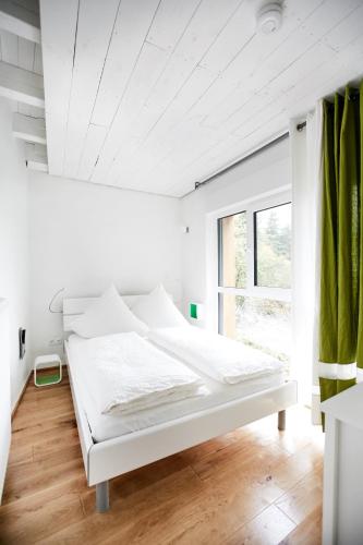 a white bed in a room with a window at Basalt-Loft in Kottenheim
