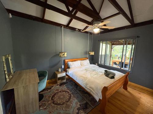 a bedroom with a bed and a table and a window at Elephant loft in Stormsrivier