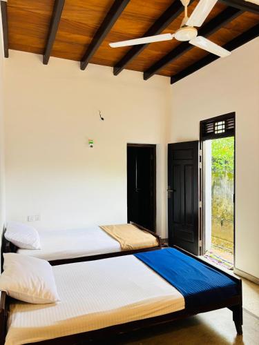 two beds in a room with a window at Pandula Villa 390 in Hikkaduwa