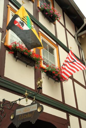 two flags on the side of a building with flowers at Hotel Abtshof in Halberstadt
