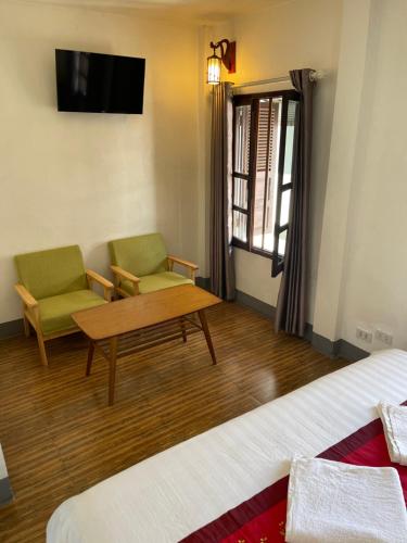 a room with two chairs and a table and a tv at Liberty Place in Luang Prabang