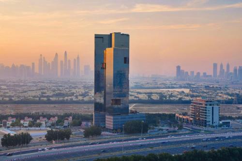 ein hohes Gebäude mit einer Stadt im Hintergrund in der Unterkunft Hotel Local Dubai, Jumeirah Village Triangle, Autograph Collection in Dubai