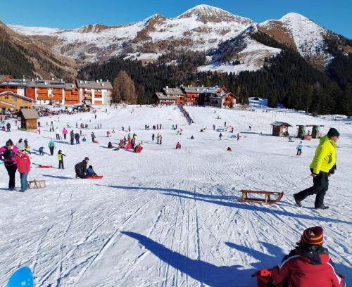 a group of people skiing and snowboarding on a ski slope at Appartamento Verdenatura in Branzi
