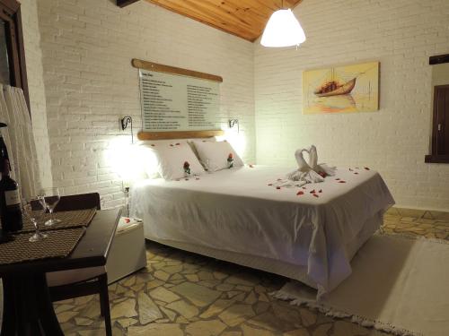 a bedroom with a bed with a table and a lamp at Pousada Cantinho das Estrelas in Monte Verde