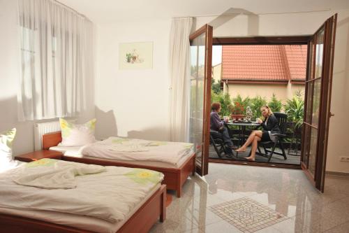 a room with two beds and a woman sitting at a table at Pensjonacik Graven in Nidzica