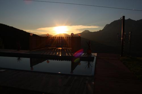a sunset over a swimming pool with the sun setting at Apparthaus Taxegger in Haus im Ennstal