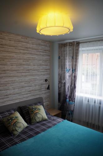 een slaapkamer met een blauw bed met een geel licht bij Jaukus butas Klaipėdos centre in Klaipėda