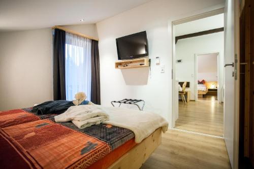 a bedroom with a bed with a television on the wall at Gästehaus Waldrand Garni in Wiesing