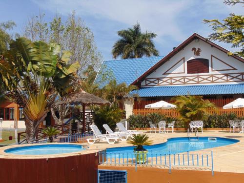 a resort with a pool and chairs and a house at Pousada Villa Da Montanha in São Bento do Sapucaí
