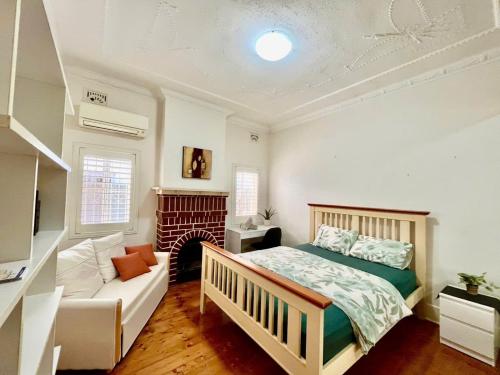 a bedroom with a bed and a couch and a fireplace at Relaxed Cosy Beach Room Close to Airport in Sydney