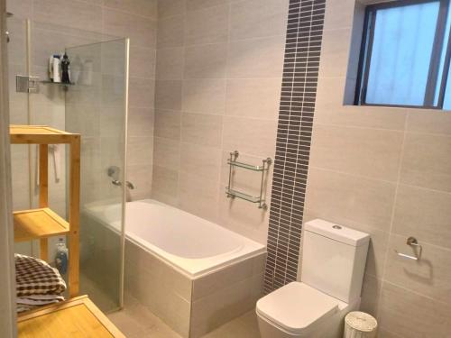 a bathroom with a tub and a toilet and a shower at Relaxed Cosy Beach Room Close to Airport in Sydney