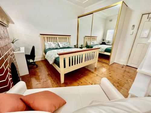 a living room with a bed and a mirror at Relaxed Cosy Beach Room Close to Airport in Sydney
