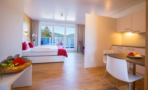 ein Hotelzimmer mit einem Bett und einer Küche mit einem Tisch in der Unterkunft Hotel Restaurant Rhy in Oberriet
