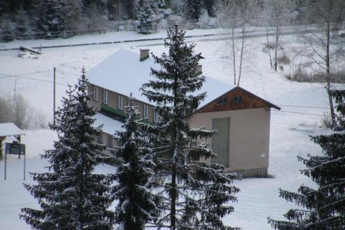 a building with snow covered trees in front of it at Pension Martinské údolí - dependance in Kořenov