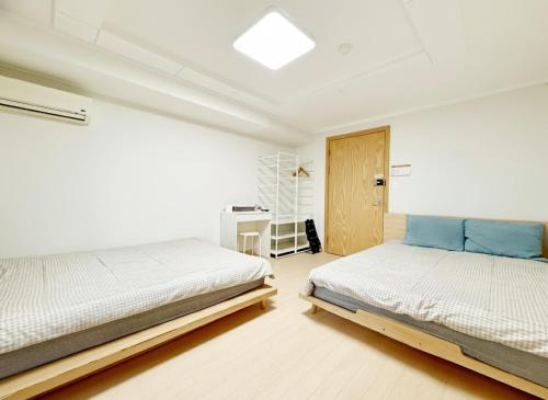 een witte slaapkamer met 2 bedden en een bureau bij Namsan Forest in Myeongdong in Seoul