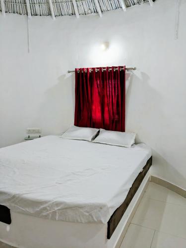 a bed in a room with a red curtain at Glory Farm in Vadāli
