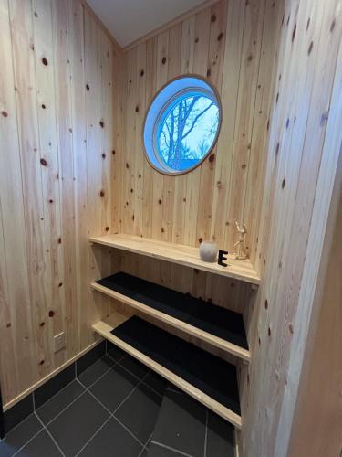 a bathroom with wooden walls and a circular window at Hakuba Powder Cottage Eden in Hakuba