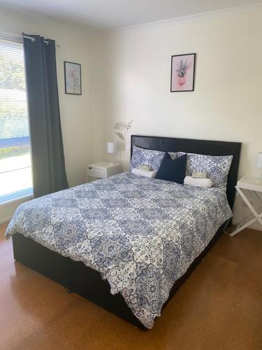 a bedroom with a bed with a blue and white comforter at Phillip Island Beach House - Relaxed - Close to Beach - Pet Friendly in Cowes