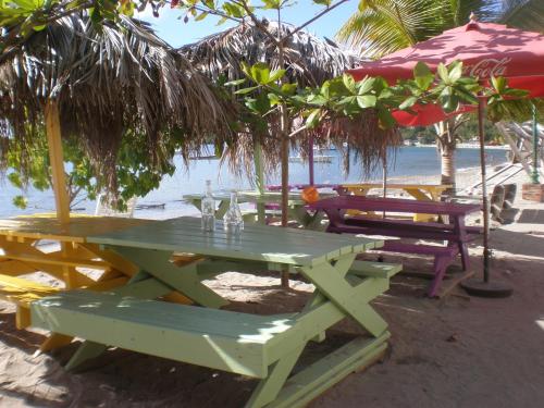a picnic table on the beach with chairs and umbrellas at Turquoise Caritan in Sainte-Anne