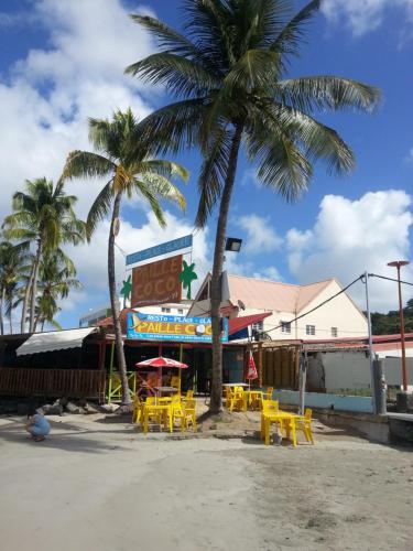 two palm trees and yellow tables and chairs on the beach at Turquoise Caritan in Sainte-Anne