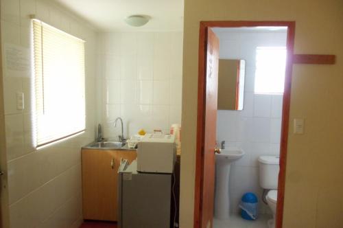 a small bathroom with a sink and a refrigerator at Acropolis Hostal in La Serena