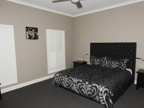 a bedroom with a black and white bed and two windows at Barklysuites Apartments in Rutherglen