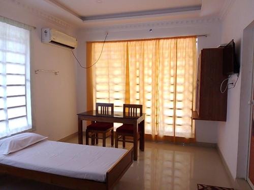 a bedroom with a bed and a table and a window at Somatheertham Resort in Kovalam