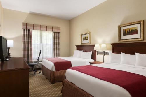 a hotel room with two beds and a television at Country Inn & Suites by Radisson, Macon North, GA in Macon