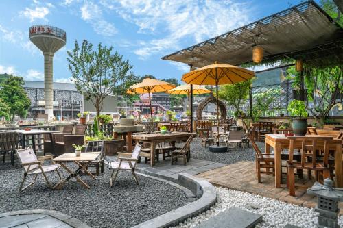 an outdoor restaurant with tables and chairs and umbrellas at Phoenix Ancient Hill Riverside View Hotel- Offers free one-way high-speed rail pick-up service - Afternoon tea - Self-service laundry - Baggage storage - Travel planning in Fenghuang County