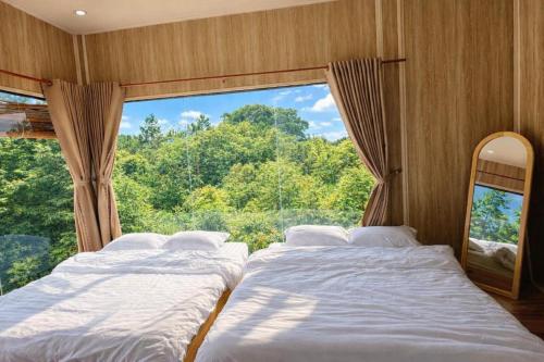two beds in a room with a large window at Han San Homestay Măng Đen in Kon Plong