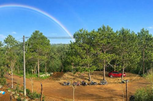 een groep motorfietsen geparkeerd op een parkeerplaats met een regenboog bij Han San Homestay Măng Đen in Kon Plong