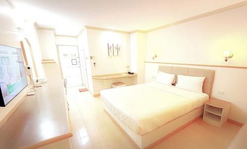 a white bedroom with a bed and a television at P.A. Ville Hotel in Nakhon Sawan