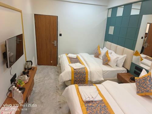 een hotelkamer met drie bedden en een televisie bij KDM Hotel Indore Palace- a walk away from Saibaba Temple in Shirdi