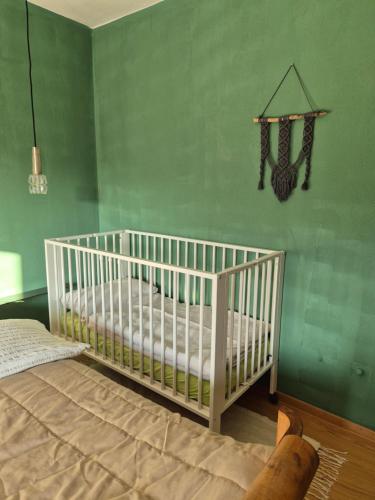 a white crib in a room with a green wall at haus nummer fünf - inklusive Chiemgau Karte in Siegsdorf