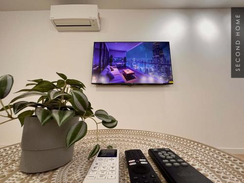 stół z dwoma pilotami i doniczkową rośliną w obiekcie Second Home - Kota Kemuning w mieście Shah Alam