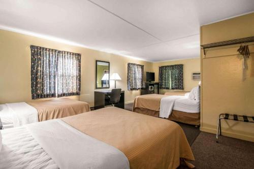 een hotelkamer met twee bedden en twee ramen bij Rodeway Inn Rutland - Killington in Rutland