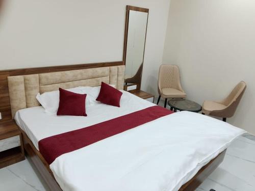a bedroom with a white bed with red pillows at Hotel Sobhagyam in Kekri