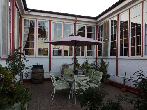 a patio with a table and chairs and an umbrella at El Mirador De Valparaiso in Valparaíso